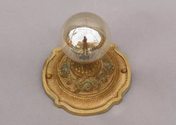 A gold plate with a glass globe on top of it.