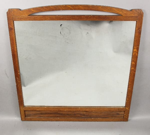 A worn wooden frame enclosing a 13613. Circa 1910 Mission Mirror With Curved Top, set against a grayish backdrop.