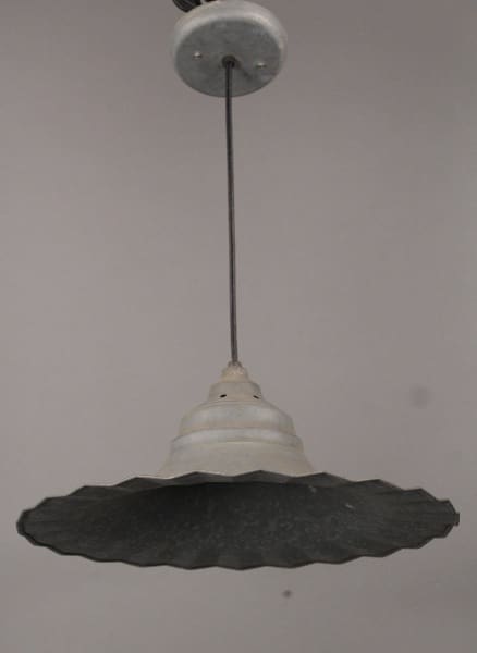 A vintage 10428. Industrial Pendant with Unusual Ruffled Edge with a wide, textured shade, suspended from a ceiling by a wire.
