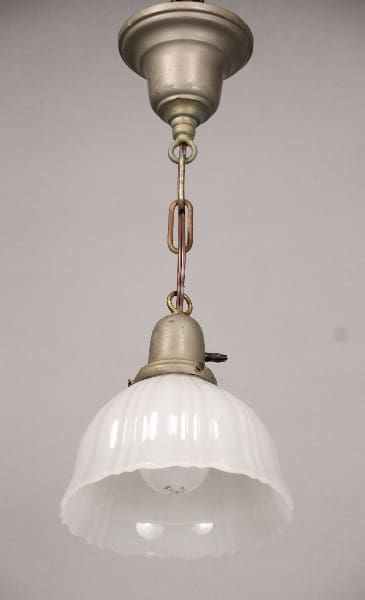 An antique 10494. HOLD pendant light featuring a frosted glass shade and a metal fixture, suspended from a ceiling mount with a chain.