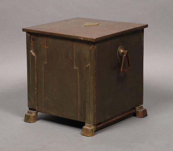 A vintage metal cabinet with a faded bronze finish and a single handle on the front, standing on short legs. 10812. Turn of the Century Coal Bin