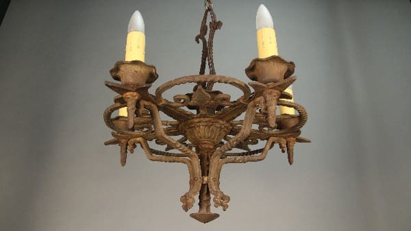 11399. 1920's Iron Chandelier With Four Lights designed to resemble branches with candle-like lights, suspended from a ceiling, against a grey backdrop.