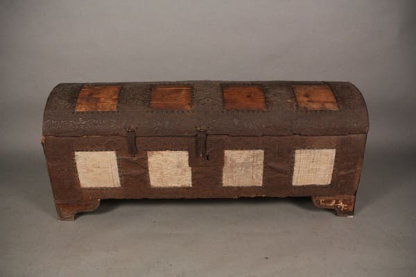 Vintage 11959. Spanish Early 19th Century Cassone trunk with iron hardware and a patchwork design of light and dark brown rectangular panels on a gray background.