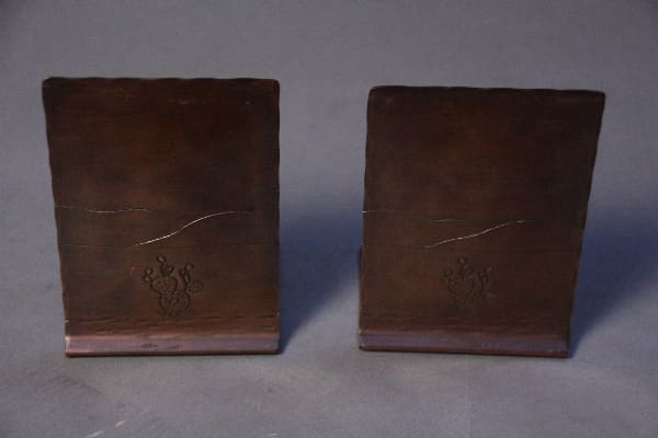 Two brown, rectangular 12010. Pair of 1920's copper bookends with cactus motif, displayed against a grey background.