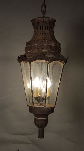 Hanging 12070. 1920's Punched Tin Lantern With Glass Panels, illuminated from within, against a neutral background.