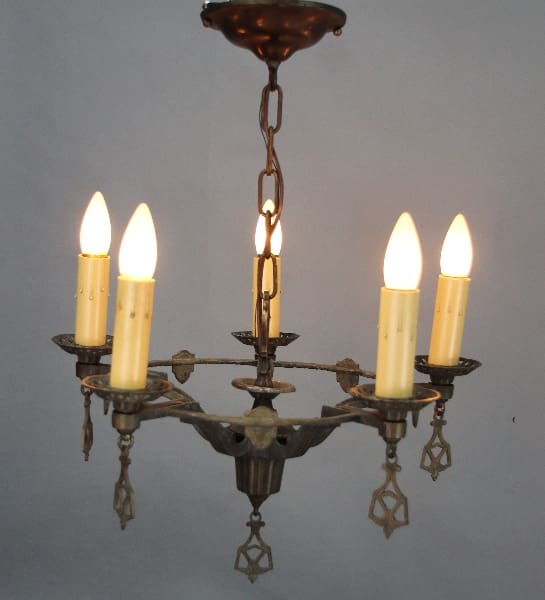 Antique 12704. 5 Light Spanish Revival chandelier with ornate metal frame and hanging crystals, against a light grey background.