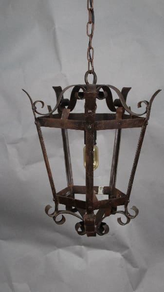 An old, rusty 13073. 1930 Simple Iron Pendant hanging from a chain against a crumpled white background.