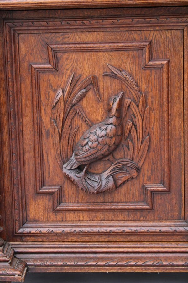 Carved court cabinet depicting a bird surrounded by foliage, set within a decorative square frame with intricate details.