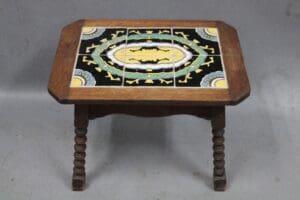 A 13981. 1920's Spanish Revival 6 Tile Table with a hexagonal top, intricately decorated with a black inlay featuring a yellow and white geometric design and central oval motif.