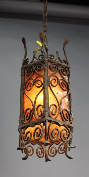 Antique wrought iron lantern with ornate scroll designs and amber glass panels, hanging from a chain. 
14002. 1920's Spanish Revival Mica Chandelier with ornate scroll designs and amber glass panels, hanging from a chain.
