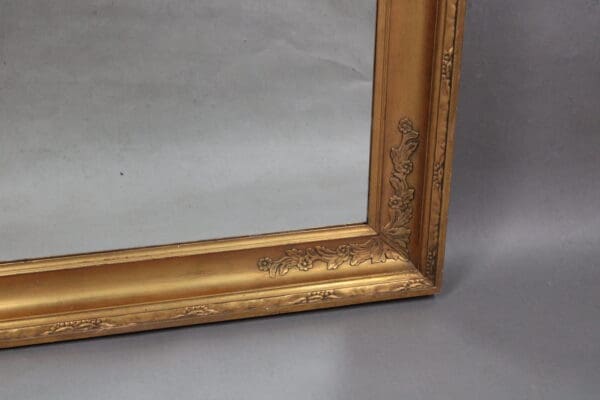 Close-up of a corner of an ornate 14172. 1920's Very Large Scale Mirror with floral embossing on a gray background.