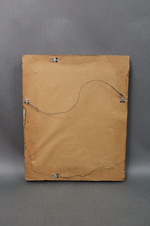 A worn cardboard back of a 14191. Turn of The century Small Mirror with Exquisite Frame with a hanging wire attached, displayed against a gray background.