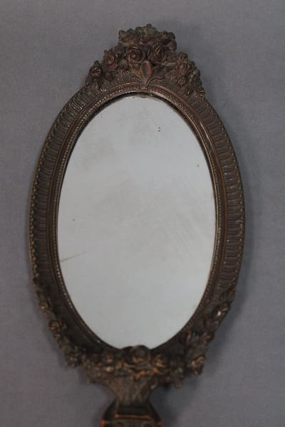 14230. 1920's Hand Held Polychrome Mirror with an ornate floral frame, displayed against a plain gray background.