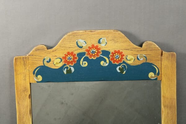 Top portion of a 14427. Monterey Period Mirror With Vibrant Painting frame with a floral design painted in vibrant colors, set against a gray background.