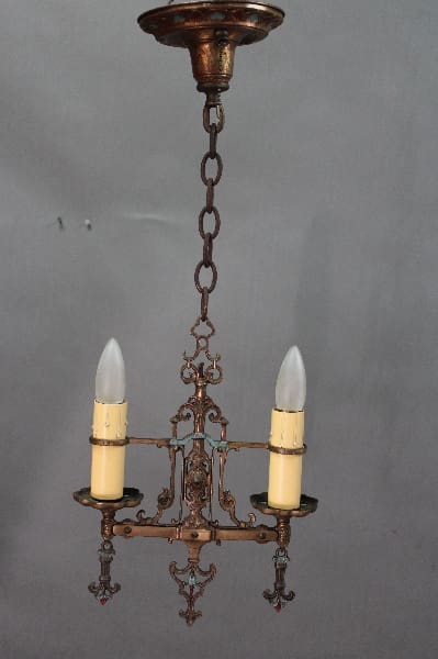 14526. 1920's Polychrome Pendant with two electric candles, intricate metalwork, and a chain hanging from a ceiling mount against a gray background.