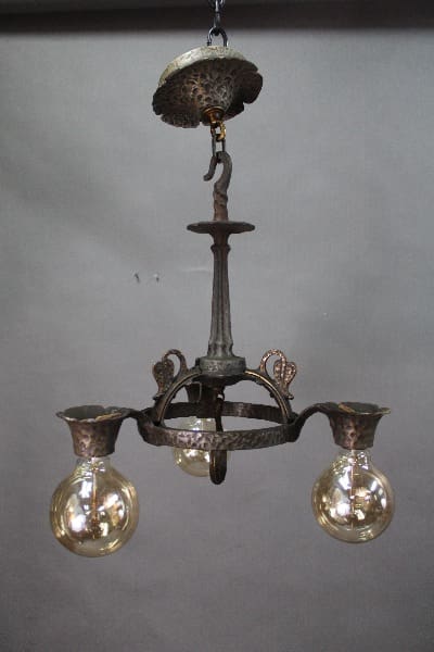 14528. 1920's Three Light Chandelier With Hammered Texture with three illuminated bulbs, suspended from a ceiling mount.