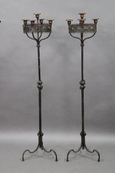 Two tall, Pair Of 1920's Wrought Iron And Brass Spanish Revival Candle Holders with intricate designs, featuring multiple candle holders on a gray backdrop.