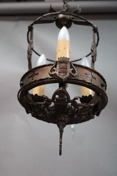 Antique chandelier with ornate metalwork and three candle-shaped bulbs hanging from a ceiling, such as the 14635. 1920's Three Light Pendant With Original Finish.