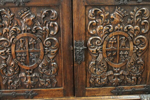 Intricately carved 14738. 1920's Carved Walnut Standing Cabinet panels featuring floral designs and circular shields, complemented by an ornate metal latch.