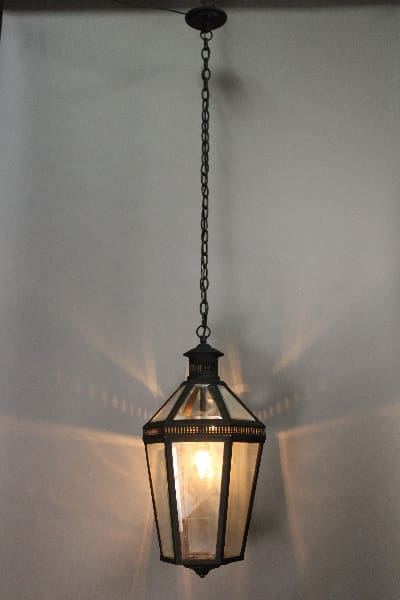 A 14871. 1920's Pendant With Seeded Glass, featuring a glass and metal lantern hanging from a chain, emitting a soft glow.