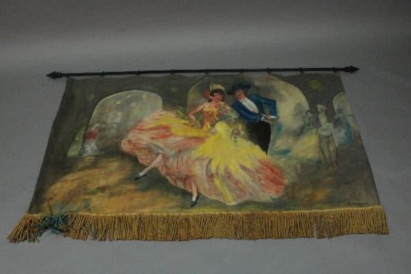 A vintage tapestry depicting a festive dance scene with a woman in a flowing orange dress and a man in a blue suit, hung on a gray background. (Product Name: 14879. Spanish Revival Hand Painted Mural And Rod)