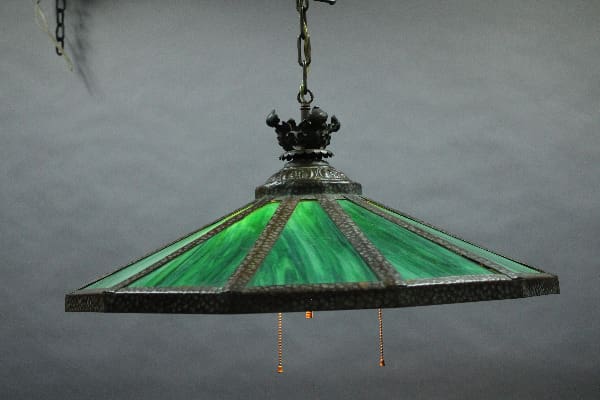 An antique 14942. Circa 1910 chandelier with green slag glass hanging from a chain, with a decorative metal crown and pull chains.