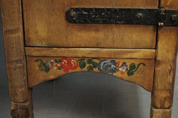 Close-up of the 15010. Signed Monterey Desk's base featuring decorative hand-painted floral accents on a curved panel between two legs.