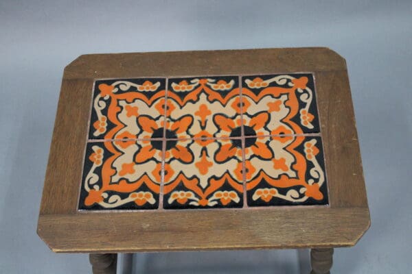 Vintage 15022. 1920's Early California Monterey Style Spanish Revival Tile Table with a square top, inlaid with six decorative, orange and black patterned ceramic tiles.