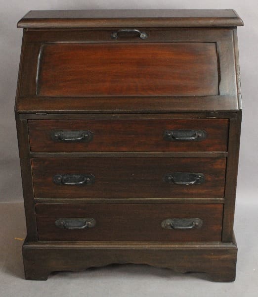 An antique 15096. 1920's Signed Monterey Desk with a slanted lift-top lid and three drawers with metal handles.