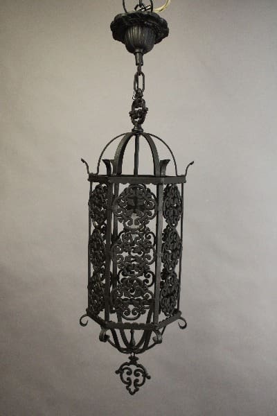 Sentence with product name: Ornate 15137. Spanish Revival 1920's Pendant with intricate scrollwork hanging from a ceiling, against a neutral background.