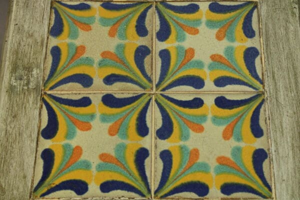 Four ceramic tiles with a colorful, floral pattern, mounted on a wooden surface.
15250. 1920's California Tile Table With Four Geometric Tiles.