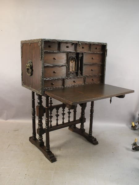15268. Spanish Revival Walnut 1920's Vargueno with multiple drawers, an open fold-down writing surface, ornate metal hardware, and turned legs, set against a plain backdrop.