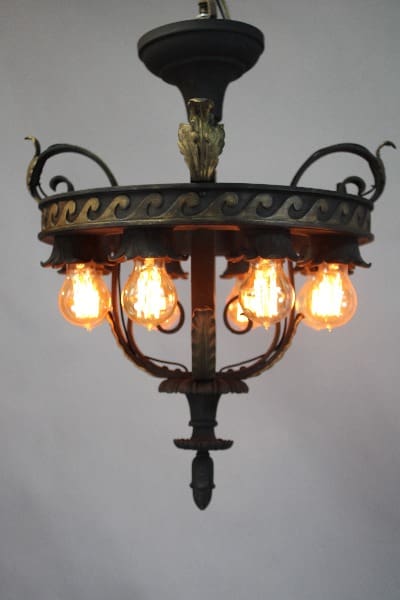 Antique 15332. 1 of 2 1920's Downlight Spanish Revival Chandelier with ornate metal frame and five glowing light bulbs, suspended from a ceiling.