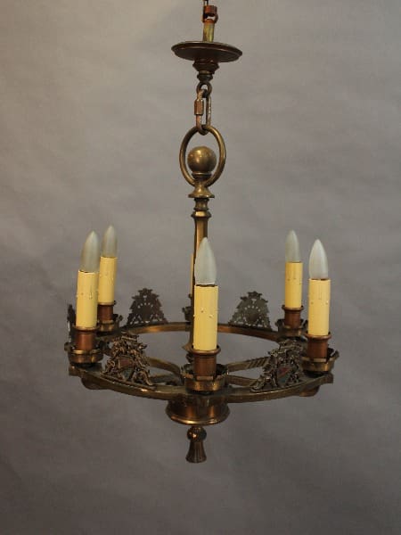 15390 Circa 1920's Bronze Polychrome Chandelier With Shield Motif with five candle-like bulbs, ornate metalwork, suspended against a plain backdrop.