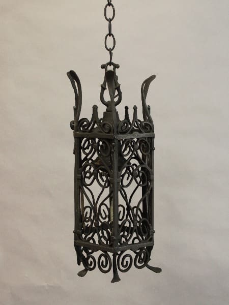 A hanging 15401. 1920's Pendant With Scroll Motif lantern with intricate scroll designs and sharp, pointed embellishments at the top.