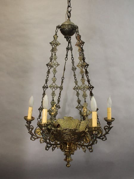 15417. Stately Turn Of The Century Bronze Chandelier with ornate metalwork and four electric candles, hanging against a gray backdrop.