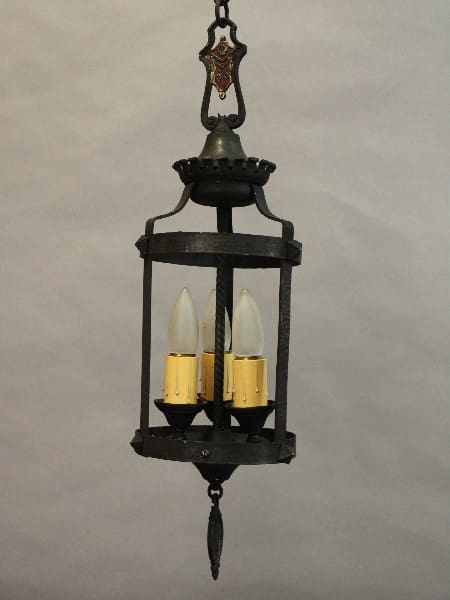 An old-fashioned hanging lantern with a 15433. Spanish Revival 1920's Pendant With Three Lights, against a plain, light background.