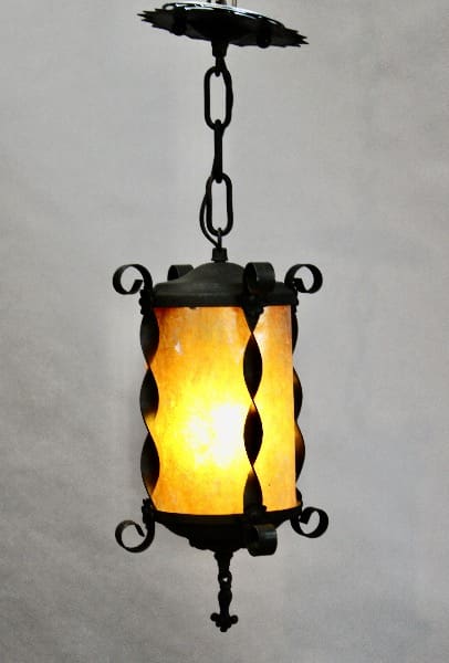 Antique 15440. 1920's Pendant With Mica hanging from a chain, illuminated from within, casting a warm glow on a light grey background.