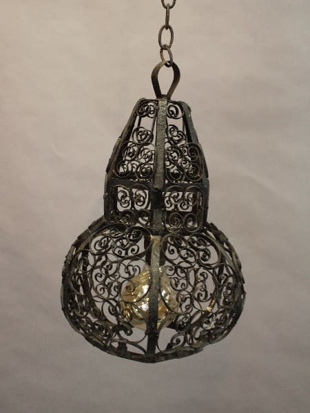An 15441. Antique Pendant With Filigree with intricate scroll designs, hanging from a chain, with a light bulb inside.
