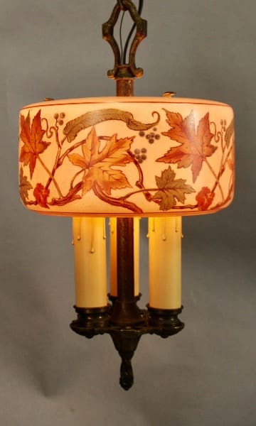 Vintage 1920's Three Light Pendant with Original Glass Shade adorned with autumn leaf designs and three candle-like bulbs, set against a grey background.