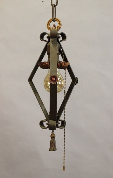 An ornate hanging light fixture with a 15486. Spanish Revival 1920's Pendant With Original Polychrome Finish, a central glass globe, and decorative elements including beads and tassels.
