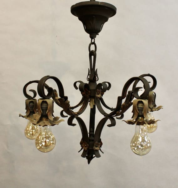 15553. Spanish Revival 1920's chandelier With Acanthus Motif with five arms, each featuring ornate leaf designs and holding a clear, illuminated bulb, against a plain backdrop.