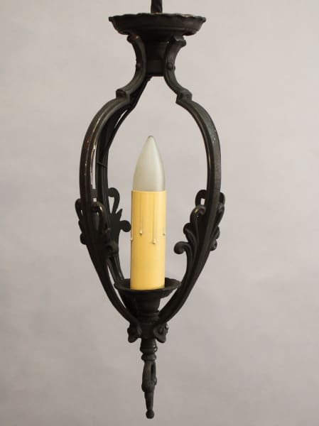 An elegant black iron wall sconce featuring ornate scrollwork designs, holding a single 15554. 1920's Small Pendant With Elegant Lines light bulb.