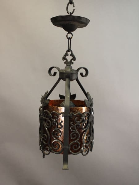An ornate, hanging 15652. Spanish Revival Pendant With Mirca with decorative scrolls and a central metal band, suspended against a plain gray background.