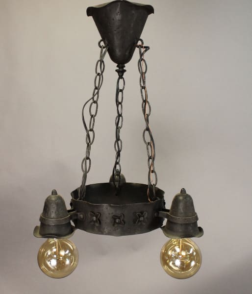 Vintage 15662 Wrought Iron Three Light Chandelier Circa 1920's with two illuminated bulbs hanging from a chain, featuring a metal frame with decorative elements.