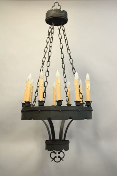 A black 15904. Rare Larger Scale Chandelier Circa 1920's with white candle-shaped lights hanging from chains against a grey wall.