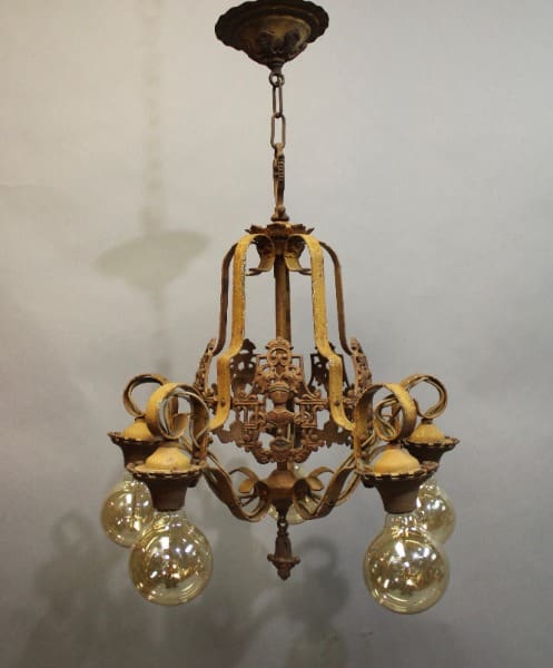 Antique 1920's Spanish Revival chandelier with knight motif, crafted in ornate metalwork and hanging from a chain, each arm holding a clear glass bulb.