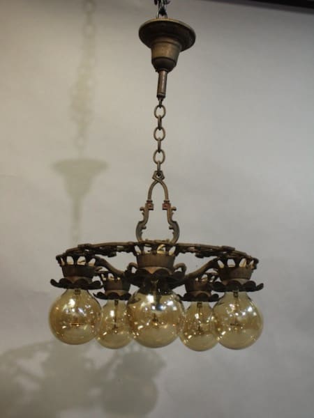 15956. Spanish Revival Down Light Chandelier With Original Finish with five glowing bulbs hanging from a chain, featuring ornate metalwork, against a plain background.