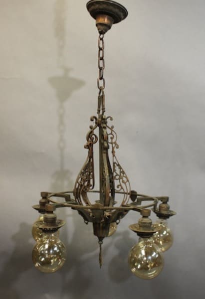 15958. Spanish Revival 1920's Chandelier With Five Lights with ornate metalwork and four glass globes hanging from a chain, against a blurred background.