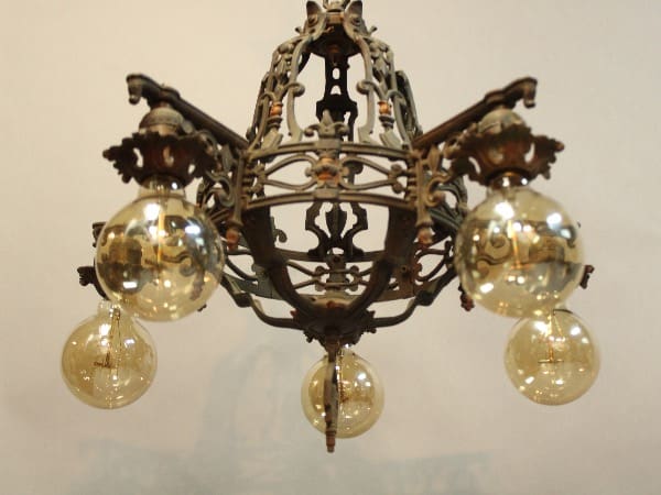 15974. Spanish Revival 1920's Chandelier With Five Arms with ornate metal design and four glowing glass bulbs.